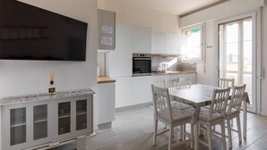 A modern kitchen with white cabinets, a dining table with chairs, and a built-in oven.