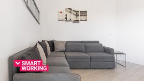 A modern living room with a grey sectional sofa, a small side table, and a wall-mounted radiator.