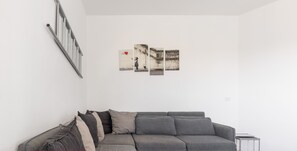 A modern living room with a grey sectional sofa, a small side table, and a wall-mounted radiator.