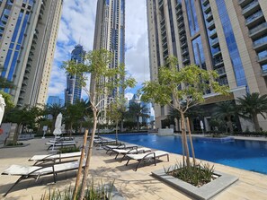 A pool area with lounge chairs and a swimming pool surrounded by tall buildings.