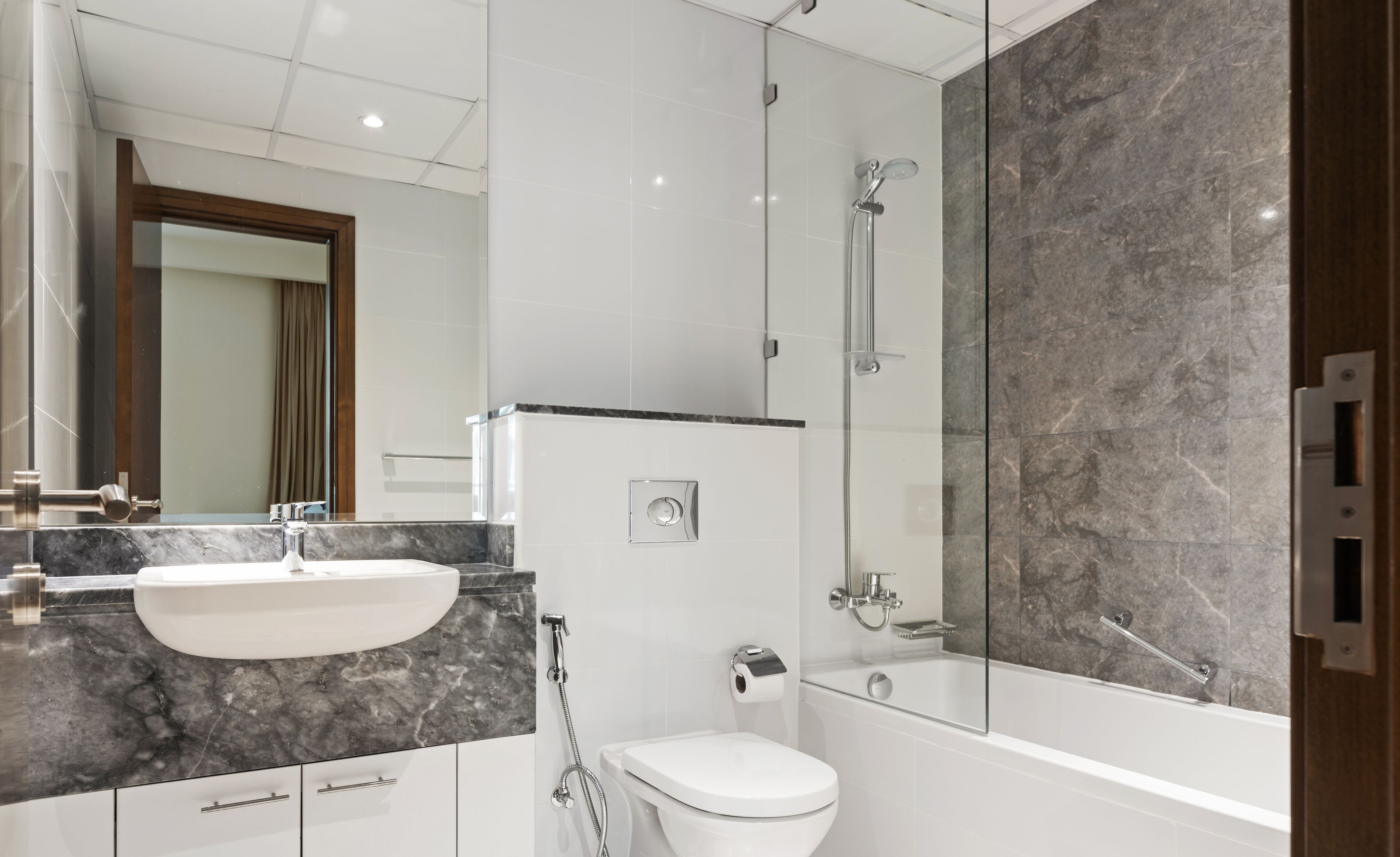Ein modernes Badezimmer mit Marmorwaschbecken, Toilette und einer Duschkabine.