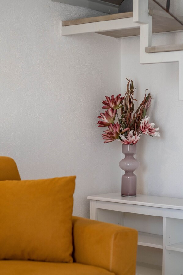 A room with a white wall, a white shelf, and a yellow sofa.
