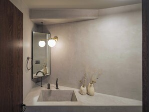 Ein modernes Badezimmer mit einem großen Spiegel, zwei Wandleuchten, einem Waschbecken und zwei dekorativen Vasen.