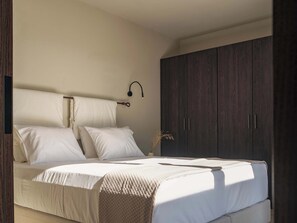 Ein Schlafzimmer mit Bett, Kissen, einer Nachttischlampe und einem Kleiderschrank.