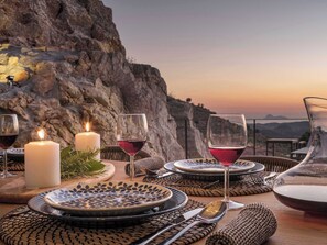 Ein Tisch ist gedeckt mit Tellern, Gläsern und Besteck, Kerzen und Blick auf eine Berglandschaft.