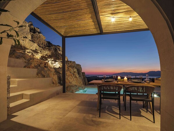 Eine Terrasse mit Esstisch, mit Blick auf einen Pool und eine Berglandschaft.