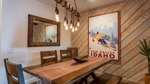 Ein Essbereich mit einem Holztisch, Stühlen, einem Spiegel und einem Poster eines Skifahrers.