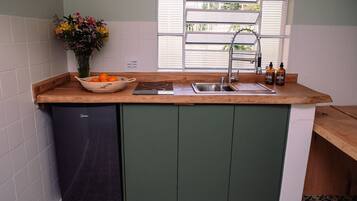 Una cocina con lavavajillas integrado, un lavamanos y una ventana con persianas.