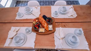 A dining table set for four with white plates, cups, and a central fruit and cheese board. - Recanto das Videiras (Itapira)
