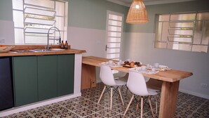 A kitchen with a wooden island, white chairs, and a patterned floor. - Recanto das Videiras (Itapira)
