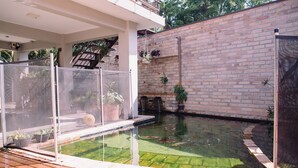 A swimming pool with a wooden deck, surrounded by potted plants and a brick wall. - Recanto das Videiras (Itapira)