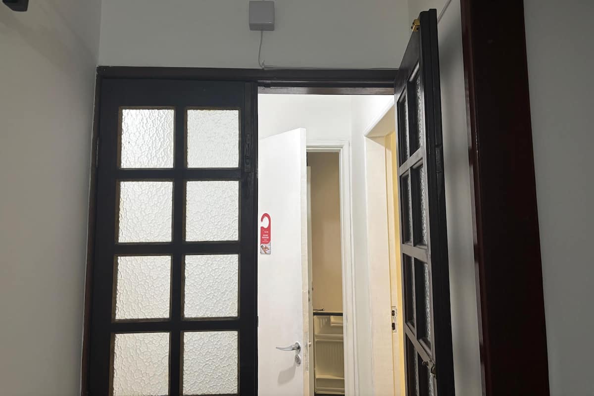 A doorway with frosted glass panels, a white door, and a small red sign on the wall.