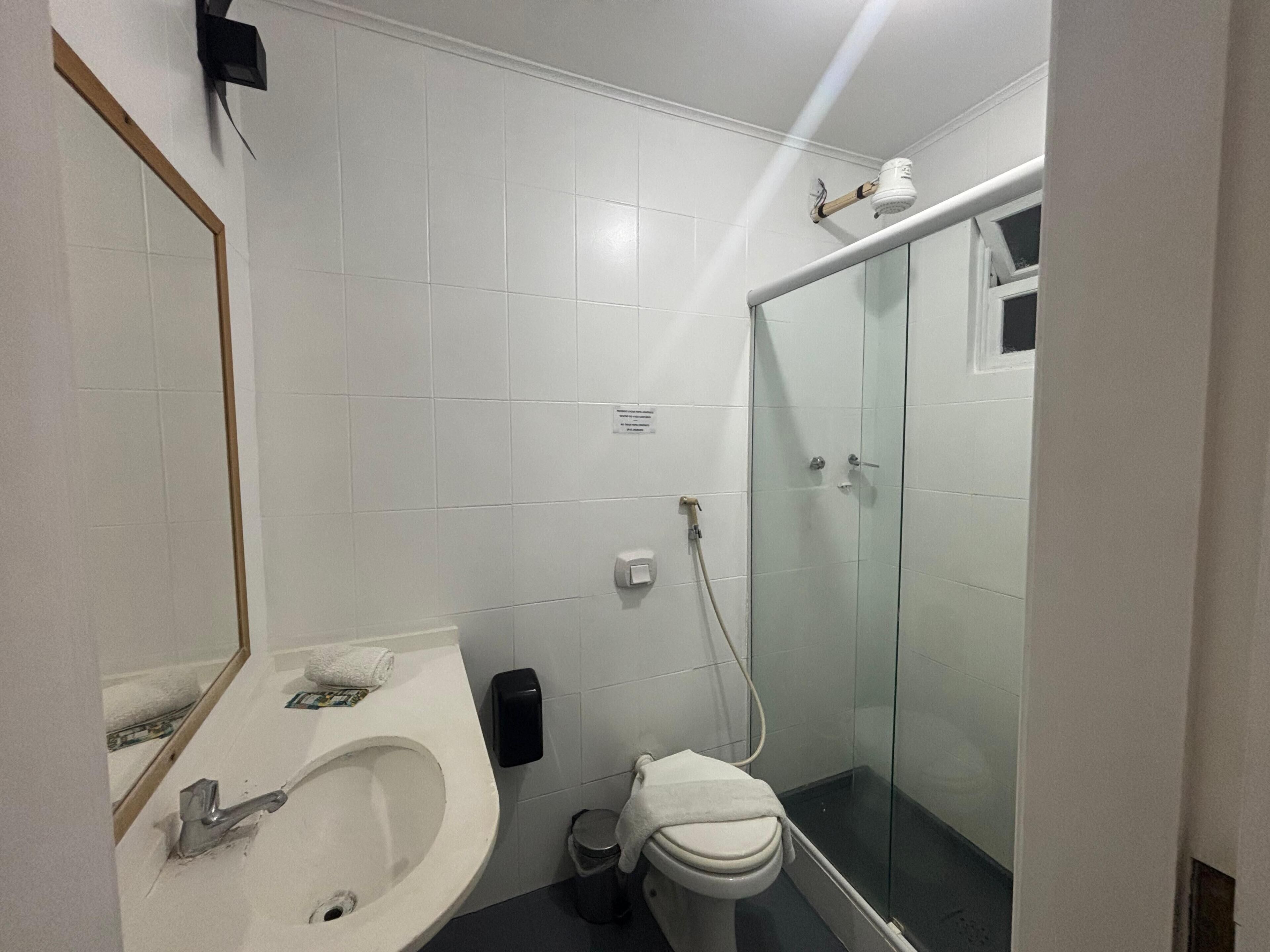 Un baño con lavamanos blanco, inodoro y cabina de ducha de vidrio.