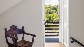 Ein Holzhocker in einer Diele mit Blick auf einen Balkon und einer Tür, die nach draußen führt.