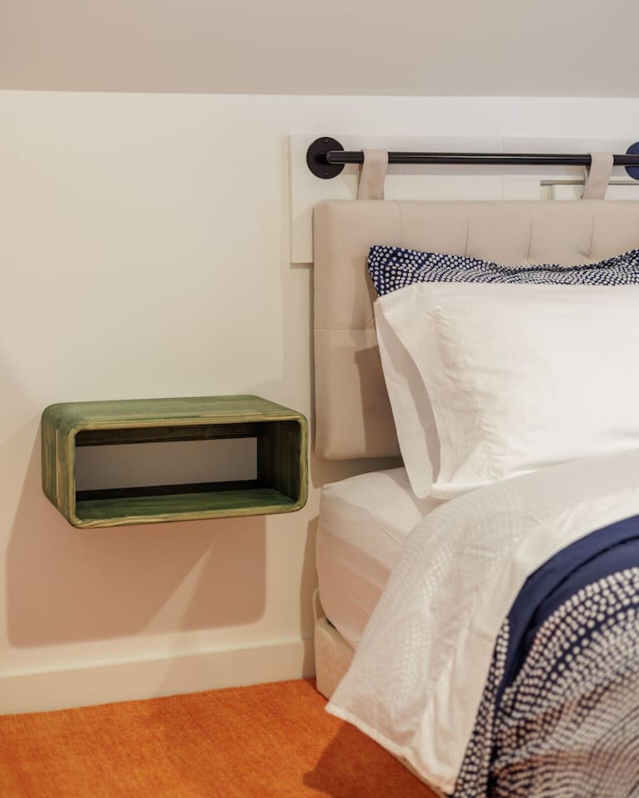 Une chambre à coucher comprenant un lit, une tête de lit, une table de chevet et une étagère fixée au mur.