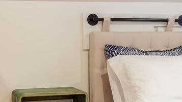 Une chambre à coucher comprenant un lit, une tête de lit, une table de chevet et une étagère fixée au mur.