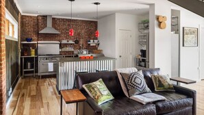A modern kitchen with a brick wall, stainless steel appliances, and a central island.