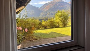 Una ventana con vistas a un campo cubierto de hierba, árboles y montañas.