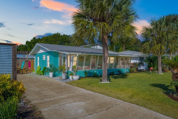 A house with a large glass window, a lawn, and a palm tree.