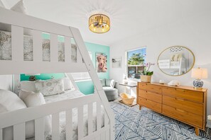 A baby room with a crib, a dresser, a mirror, and a window with a view of the outdoors.
