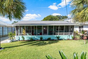 A single-story house with a covered porch, a small front yard, and a palm tree.