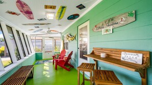 A room with a green floor, wooden furniture, and surfboards on the ceiling.