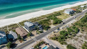 An aerial view of a coastal area with a beach, a road, and buildings.