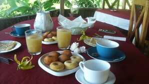 Una mesa lista para el desayuno, con platos de comida, vasos de jugo y una jarra de leche.