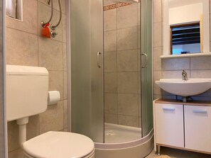 A bathroom with a toilet, a glass-enclosed shower, and a sink. - Apartment Ivan (Rovinj)