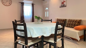 A dining area with a round table, chairs, a clock, and a sofa. - Apartment Ivan (Rovinj)
