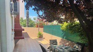 A patio with a tiled floor, a table with chairs, and a green wall. - Apartment Ivan (Rovinj)
