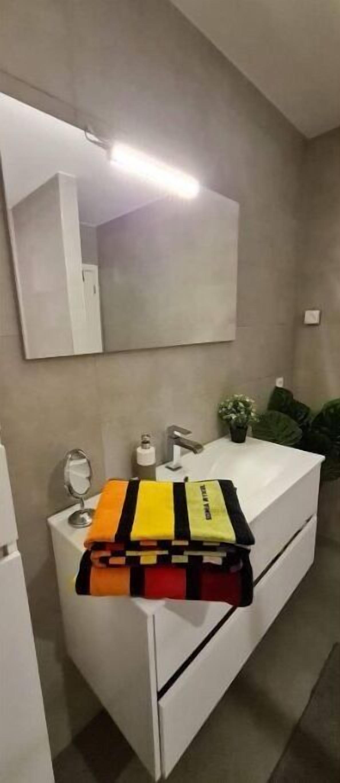 Une salle de bain avec un lavabo blanc, un miroir et un porte-serviettes.