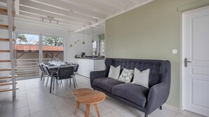 Una sala moderna con un sofá gris, una mesa de centro de madera y una zona de comedor con sillas y una mesa.