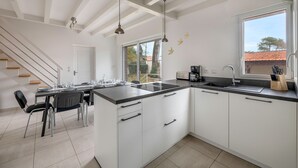 Una cocina moderna con armarios blancos, encimera negra y un amplio ventanal.