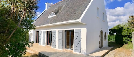 A white house with a grey roof, large sliding doors, and a small porch.