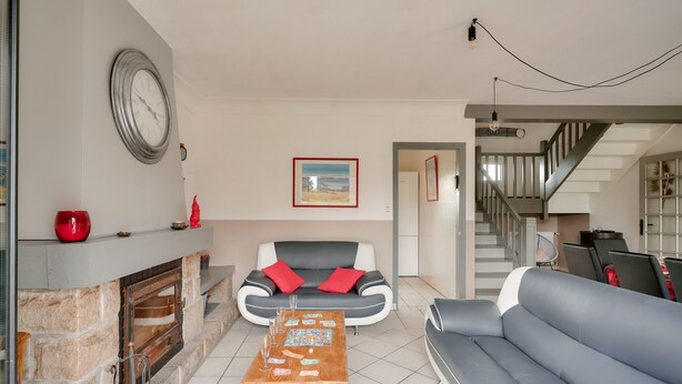 Un salon avec une cheminée, un canapé, une table basse et un escalier.