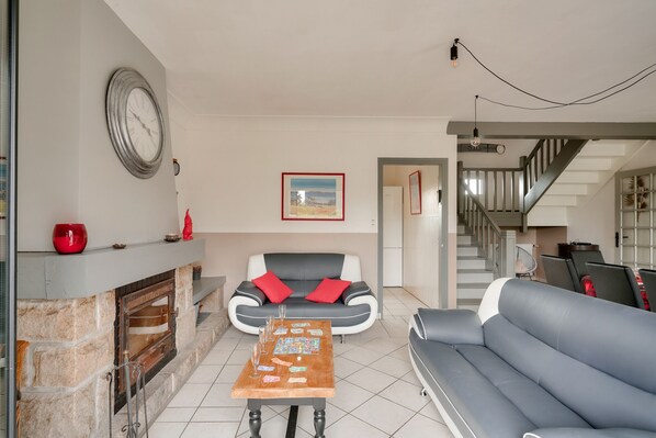 A living room with a fireplace, a sofa, a coffee table, and a staircase.