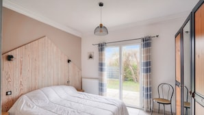 Un dormitorio con una cama grande, una silla, un radiador y vistas al exterior.