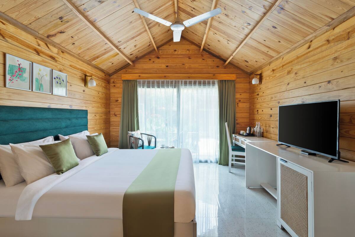 Une pièce de style cabane en bois, comprenant un lit, un bureau, une télévision et un ventilateur de plafond.