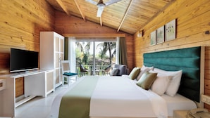 Habitación de cabaña de madera con cama, televisión y balcón con sillas.