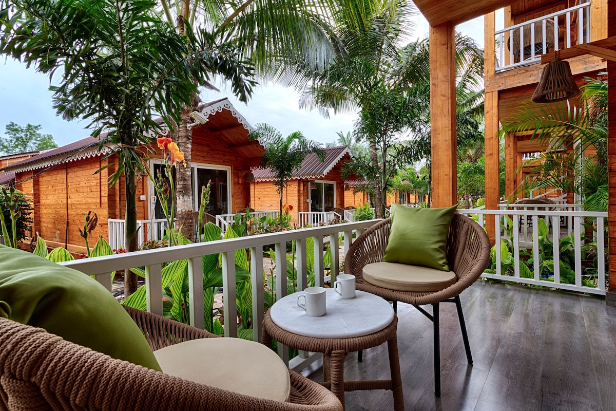 Een houten gebouw met een balkon, rieten meubilair en tropische planten.