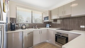 A modern kitchen with stainless steel appliances, a dishwasher, and a built-in oven. - Bridgeview - Relaxing Getaway Near Surf Beach, Lake and Sand (Lake Cathie)