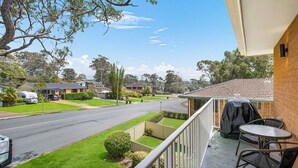 A residential street with houses, a clear sky, and a balcony with outdoor furniture. - Bridgeview - Relaxing Getaway Near Surf Beach, Lake and Sand (Lake Cathie)