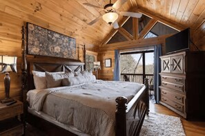 A wooden cabin bedroom with a bed, dresser, and television.