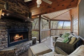 A cozy cabin with a stone fireplace, wicker furniture, and a wooden deck.
