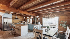 A spacious kitchen with wooden beams, a large island, and modern appliances. - Beautiful Log Cabin, Pond adjacent on Big Bear Golf Course  (Big Bear Lake)