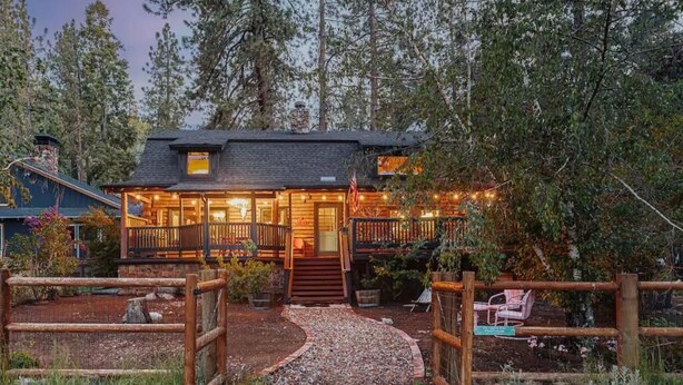 A lodge with a wooden deck, a covered porch, and a stone pathway leading to the entrance. - Beautiful Log Cabin, Pond adjacent on Big Bear Golf Course  (Big Bear Lake)