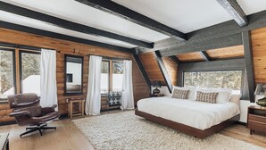 A bedroom with a large bed, wooden beams, a desk, and a chair. - Beautiful Log Cabin, Pond adjacent on Big Bear Golf Course  (Big Bear Lake)
