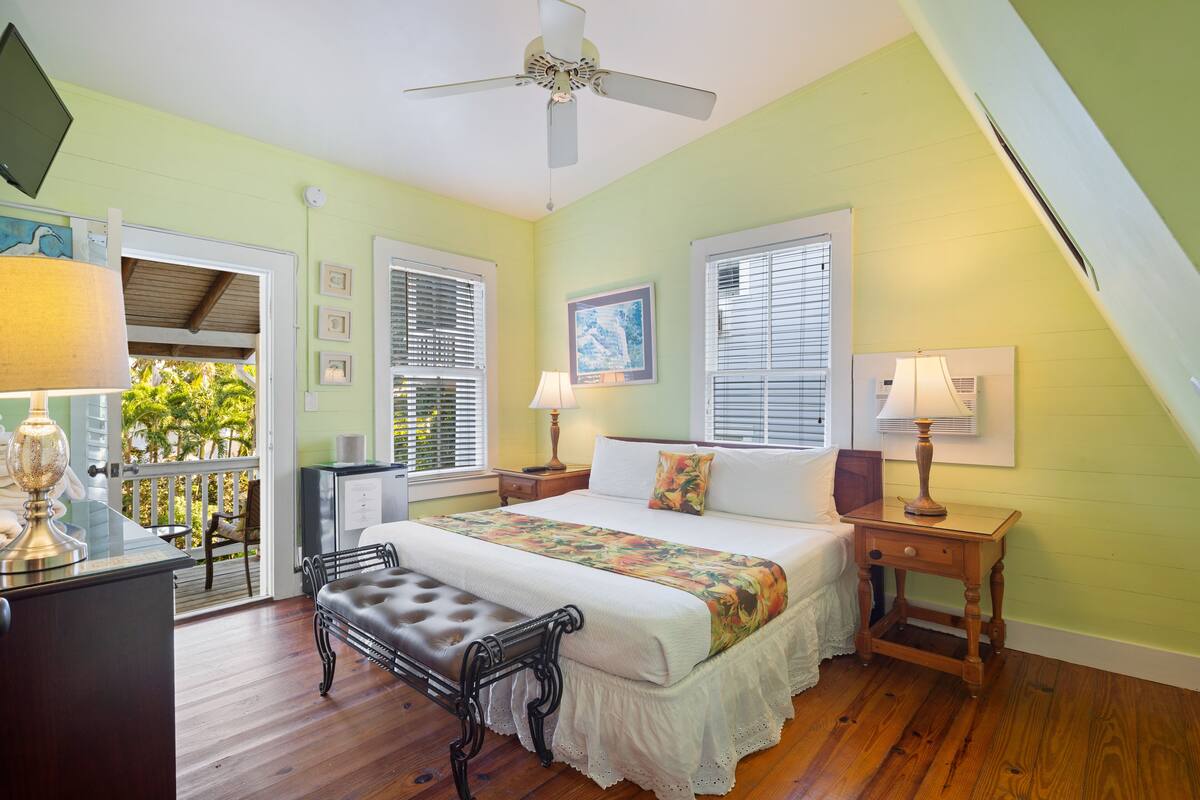 A bedroom with a bed, bedside tables, a bench, and a ceiling fan.