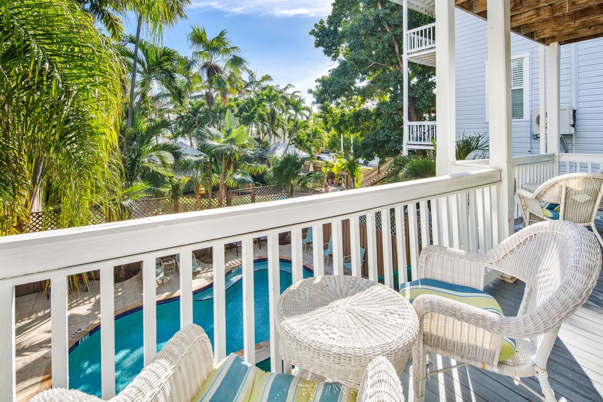 A poolside area with wicker furniture and a view of a swimming pool.